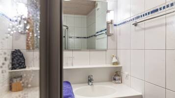 A bathroom with a white sink, a mirror, and a shower area.