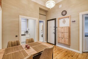 A dining area with a wooden table, chairs, and placemats. There is a door with a decorative panel and a clock on the wall. - Premium House, 3BR, Renovated, Best Loc Kadıköy (Kadıköy)
