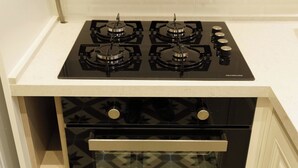 Una cocina con estufa de gas de cuatro quemadores y horno empotrado.