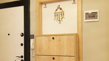 A wooden cabinet with three drawers, a wall clock, and a small plaque on a beige wall.