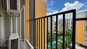 A balcony with a view of a residential area, including a swimming pool and high-rise buildings.