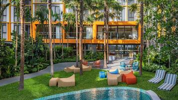 A pool area with lounge chairs and a building with yellow and white exterior.