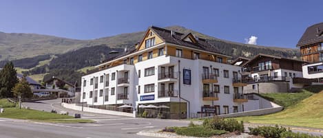 A multi-story hotel with balconies, a restaurant, and a sign for 'ALPS KITCHEN.'