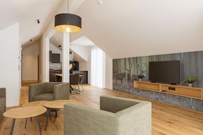 A modern living room with a high ceiling, a dining area, and a kitchen in the background. - Ofs_f_prem._mh_2sz_m.b._fis_14 (Fiss)