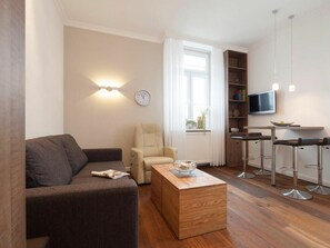 Ein modernes Wohnzimmer mit einer Couch, einem Couchtisch, einem Sessel und einem an der Wand befestigten Fernseher.