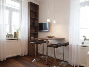 Eine moderne Küche mit einer Sitzecke an einem Holzbalken, einem an der Wand befestigten Fernseher und einem Fenster mit Vorhängen.