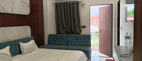 A modern bedroom with a bed, a seating area, a TV, and an air conditioning unit.