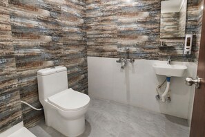 A bathroom with a toilet, a sink, and a shower area. - Deluxe Restaurant Inn (Faizabad)