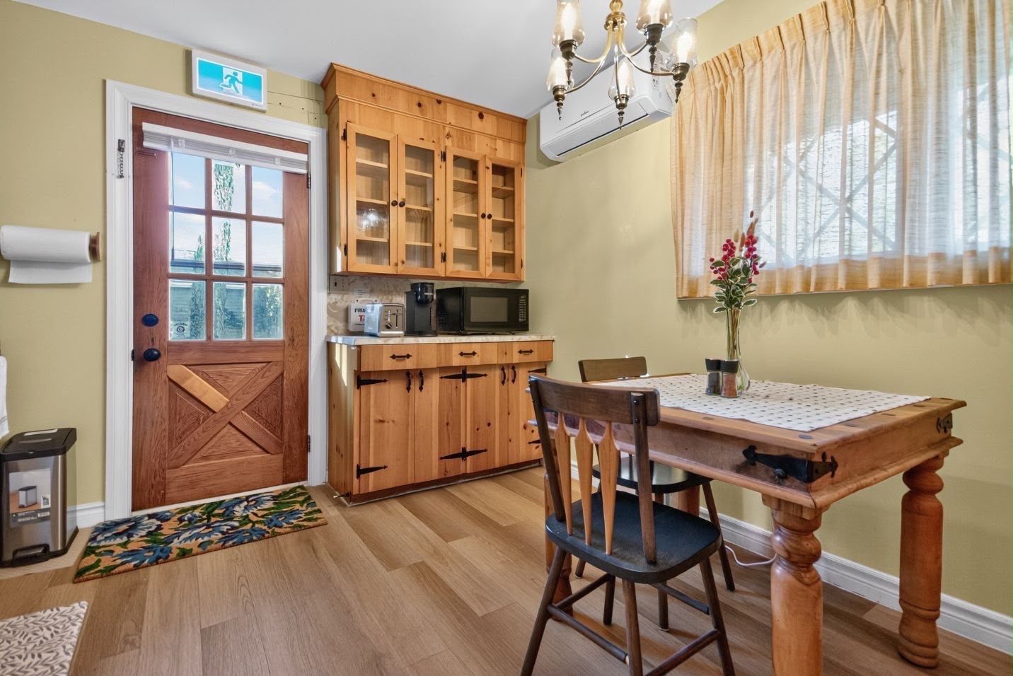 A kitchen with wooden cabinets, a microwave, and a dining table with chairs.