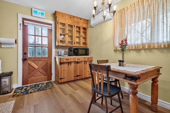 A kitchen with wooden cabinets, a microwave, and a dining table with chairs.