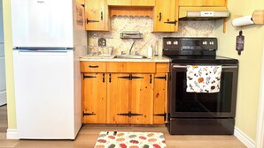 Una cucina con mobili in legno, un frigorifero bianco, un piano cottura nero e un tappeto decorato.