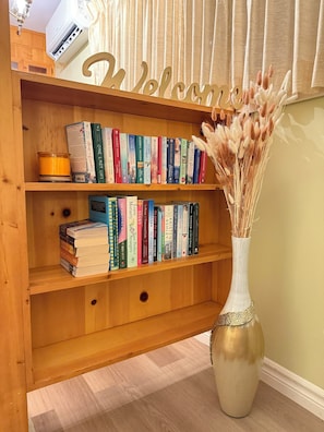 Une bibliothèque en bois avec des livres et un vase contenant des fleurs séchées.