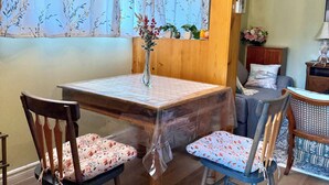 Zona pranzo con tavolo, sedie, lampadario e finestra con tende.