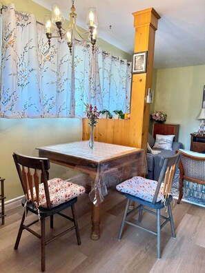 Un coin repas comprenant une table, des chaises, un lustre et une fenêtre avec des rideaux.