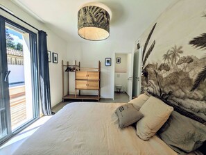 Ein Schlafzimmer mit Bett, Kleiderschrank, Bad und einem großen Fenster.
