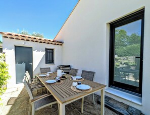 Eine Terrasse im Freien mit einem Holztisch, gedeckt für vier Personen, umgeben von Stühlen.