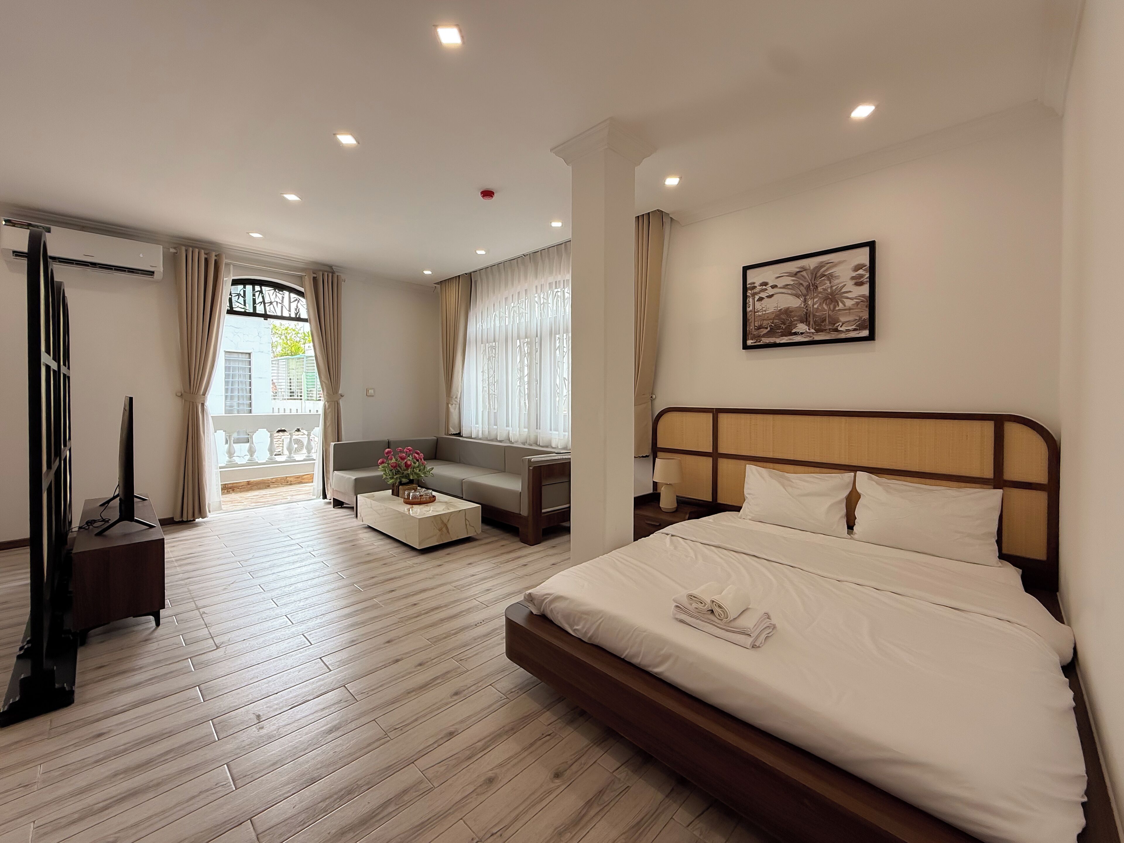 Une chambre d’hôtel avec un lit, un canapé, une télévision et un balcon avec des rideaux.