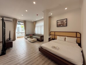 A hotel room with a bed, a sofa, a TV, and a balcony with curtains. - Maison - Product by Qunh Khang (Tân Sơn Hòa)