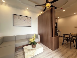 A modern living area with a sofa, a marble coffee table, a decorative plant, a ceiling fan, recessed lighting, and a dining area with chairs and a table. - Maison - Product by Qunh Khang (Tân Sơn Hòa)