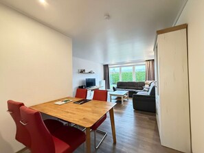 Et moderne opholdsrum med spiseplads, sofa og fjernsyn.
