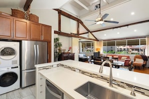 A modern kitchen with stainless steel appliances, a large island with a sink, and a dining area with a view. - Elegant top-floor unit with central AC; Haleakala Shores, steps from Kam 3 beach (Kihei)