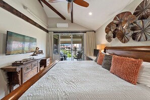 Ein Hotelzimmer mit einem großen Bett, einem Deckenventilator, einem Flachbildfernseher, einer Holzkommode und einem Balkon mit Sitzgelegenheit.