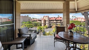 Varanda com mesa e cadeiras, vista de uma área residencial com edifícios e vegetação.