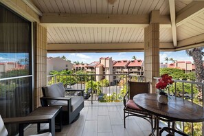 Ein Balkon mit Tisch und Stühlen, Blick auf eine Wohngegend mit Gebäuden und Grünflächen.