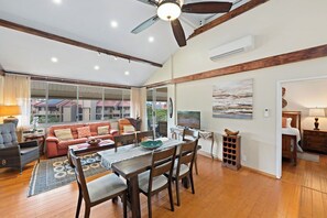 A spacious living area with a dining table, chairs, a sofa, and a television. - Elegant top-floor unit with central AC; Haleakala Shores, steps from Kam 3 beach (Kihei)