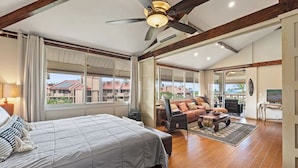 Um quarto espaçoso com uma cama grande, um ventilador de teto e vista para o exterior.