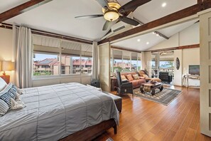 Ein geräumiges Schlafzimmer mit einem großen Bett, einem Deckenventilator und Blick ins Freie.