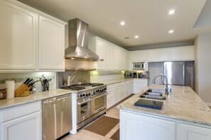 Una cocina moderna con electrodomésticos de acero inoxidable, armarios blancos y encimera de granito.