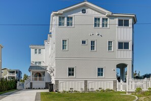 Ein mehrstöckiges Wohngebäude mit symmetrischer Fassade, zahlreichen Fenstern und einem zentralen Eingang mit dekorativem Bogen.