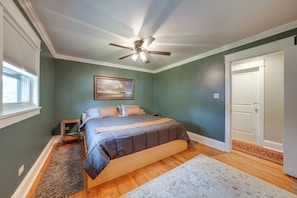 A bedroom with a bed, a ceiling fan, a painting, and a door. - Peaceful Joliet Retreat Near Dtwn & Route 66 (Joliet)