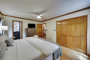 Quarto com uma cama grande, guarda-roupa de madeira e ventoinha no teto.