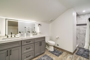Ein Badezimmer mit einem großen Spiegel, einem Waschbecken mit mehreren Wasserhähnen, einer Toilette und einer Duschkabine.