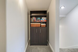 A narrow hallway with a dark wooden cabinet containing books and board games. - Mtn-Views! Flagstaff Extended Escape Near Hiking (Flagstaff)