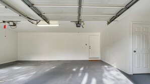 Un garaje espacioso con piso de concreto, puerta blanca y raíles para la puerta.
