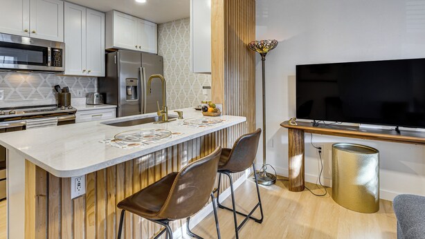 Una cocina moderna con una isla central, electrodomésticos de acero inoxidable y un televisor de pantalla plana grande.