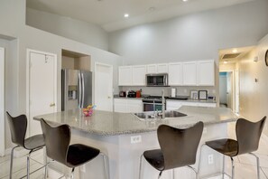 A modern kitchen with a central island, stainless steel appliances, and bar stools. - Mountain-View Patio: 11 Mi to F1 Circuit (North Las Vegas)