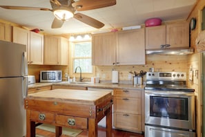 A kitchen with wooden cabinets, a refrigerator, a microwave, a sink, a stove, and a ceiling fan. - Rustic & Waterside Family Cabin in Lac Du Flambeau (Lac Du Flambeau)