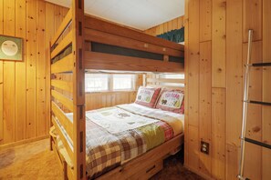 A bunk bed with a wooden headboard and a lower bunk. There is a window with blinds, a wall-mounted clock, and a door with a metal handle. - Rustic & Waterside Family Cabin in Lac Du Flambeau (Lac Du Flambeau)