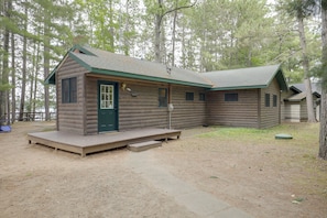A log cabin with a green door, a small porch, and a covered outdoor seating area. - Rustic & Waterside Family Cabin in Lac Du Flambeau (Lac Du Flambeau)