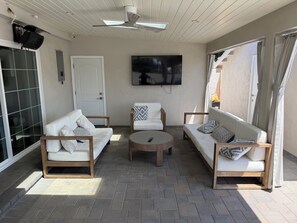 Eine sonnendurchflutete Terrasse mit zwei Sofas, einem Couchtisch und einem Deckenventilator.