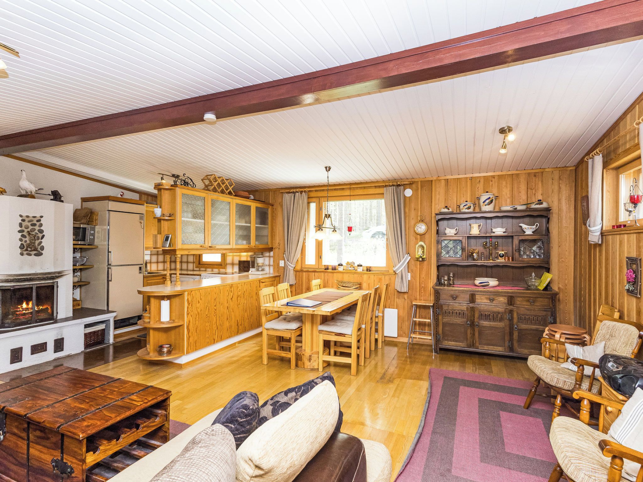 A cozy cabin interior with a wooden dining area, a fireplace, and a kitchen with wooden cabinets.