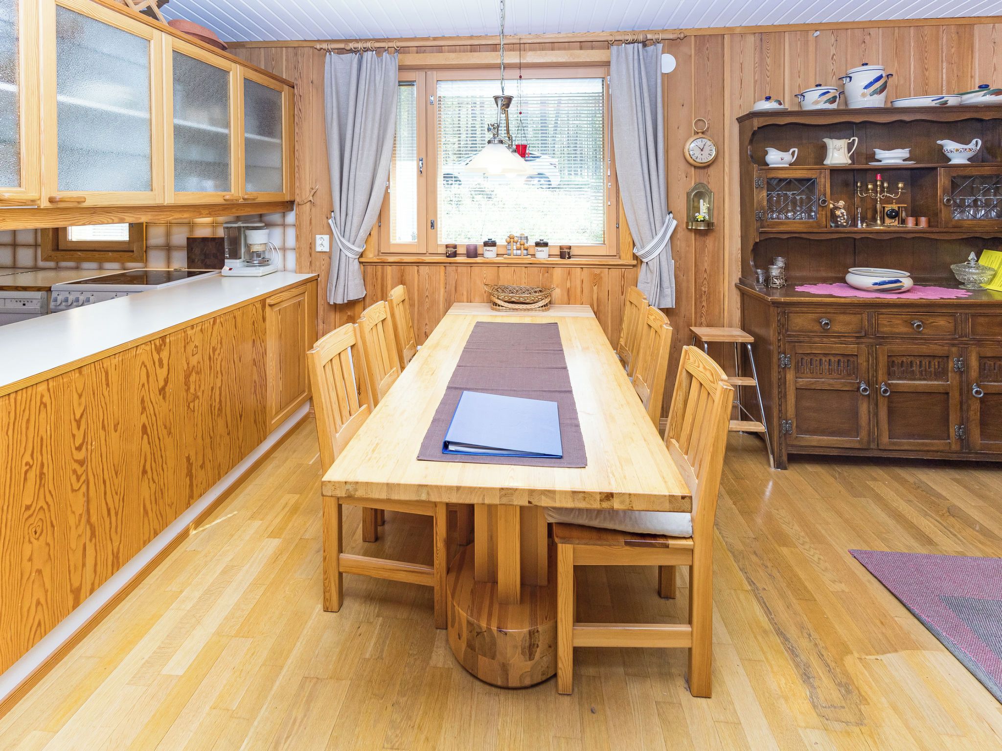 A wooden dining area with a table, chairs, and a kitchen with wooden cabinets and a window.