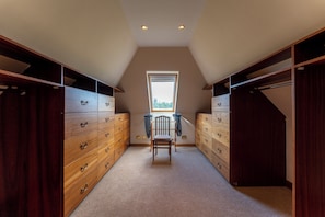 A walk-in closet with wooden drawers and a chair in the center. - St Michael's: Ben Ledi Views, Walk to Pubs & Explore Central Scotland (Kippen)