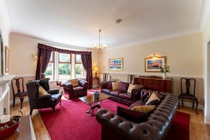 A spacious living room with leather sofas, a coffee table, and a fireplace. - St Michael's: Ben Ledi Views, Walk to Pubs & Explore Central Scotland (Kippen)