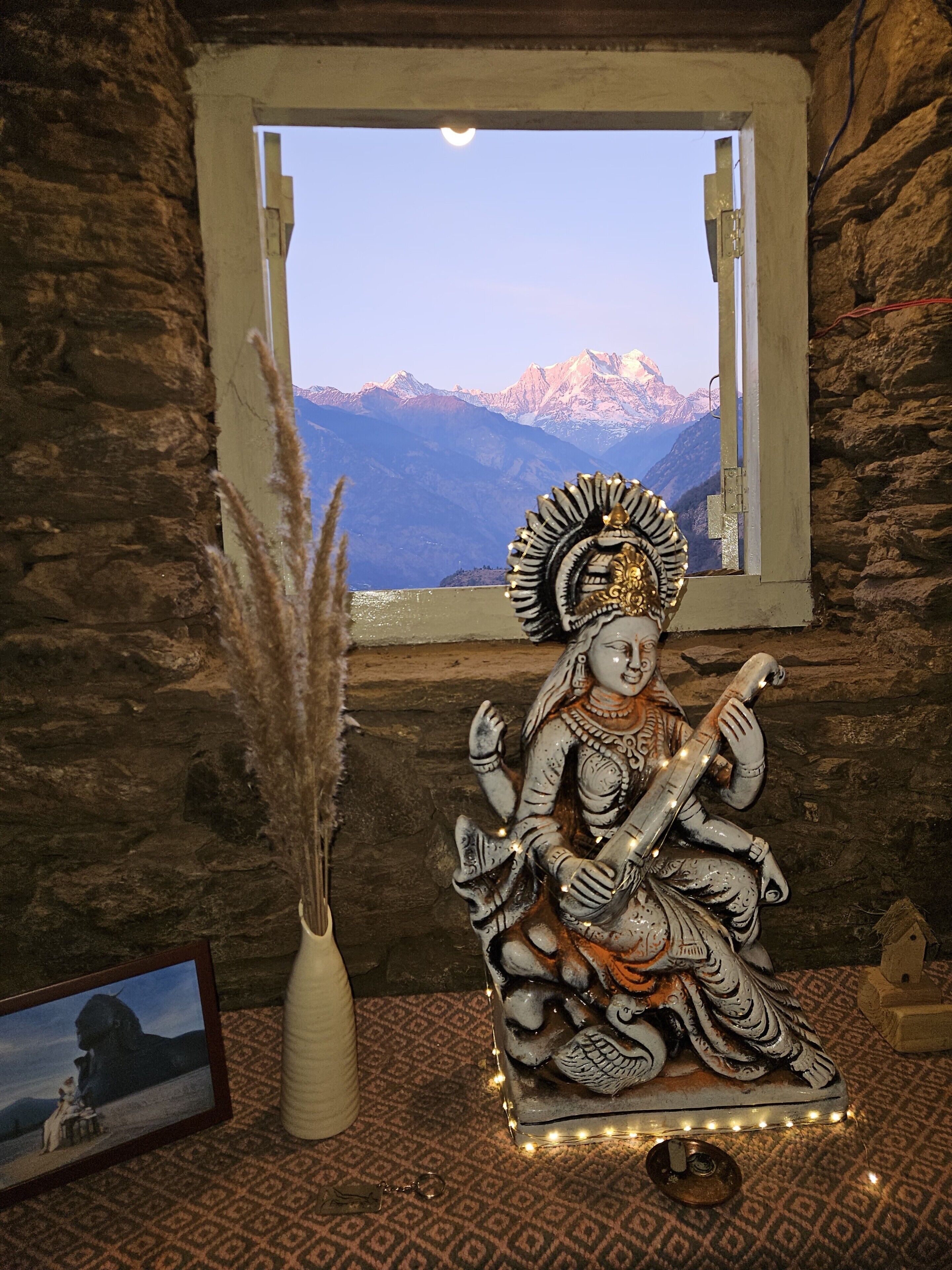 Una statua di una divinità con braccia multiple, un copricapo decorativo e sullo sfondo montagne.