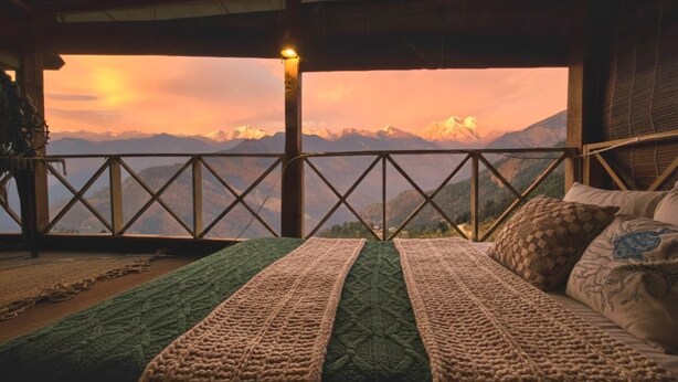 Una cama con vistas a las montañas al atardecer.